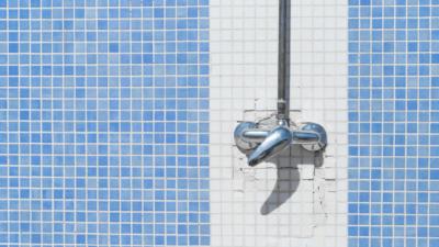 Shower wall with blue and white tile and faucet handles